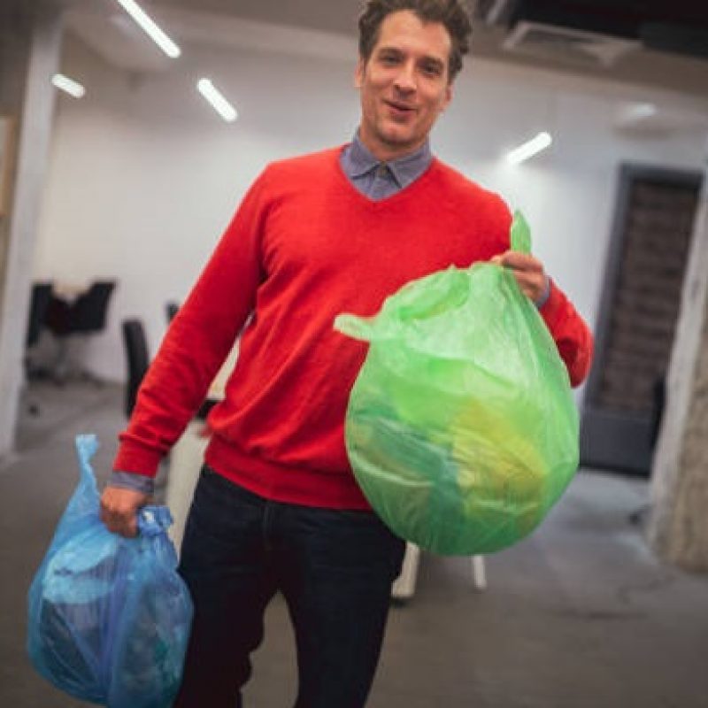 A view at a young corporate employee caught off his work routine. He's taking a break to stretch his legs and take out the trash while on the move.